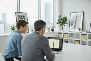 Happy graphic designer and client with their backs to the camera, looking at a laptop in a modern graphic design studio with the Menu on the screen. View shows the screen with the menu in an application